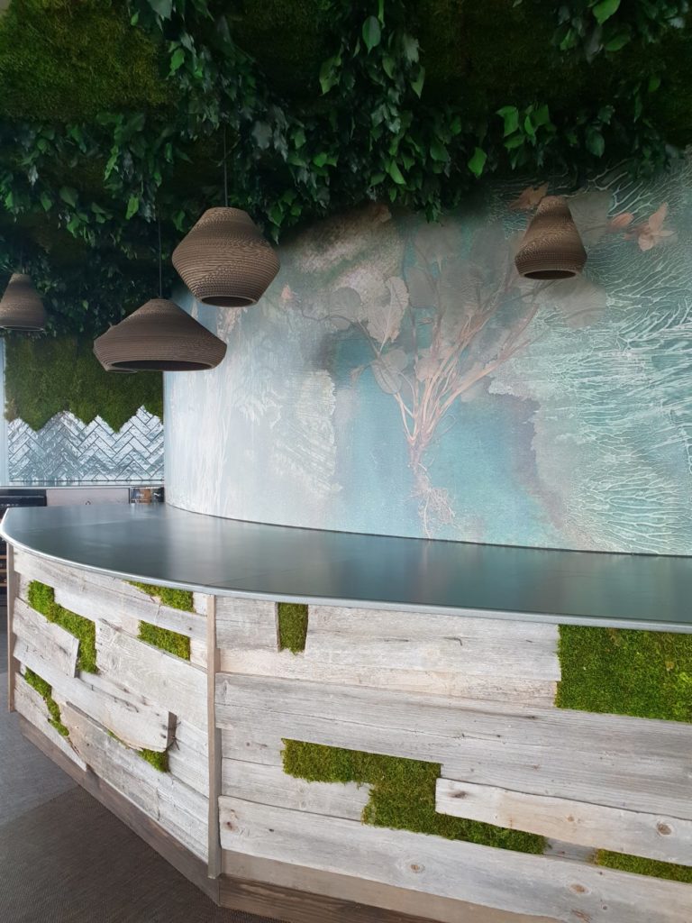 Puijon torniravintola buffet tiski, joka vuorattu kelopuulla ja sammaleella. Viherkatto sammaleesta ja lehdistä yhdessä paperivalaisimien kanssa. Seinällä tumman vihreä luontokuosinen valokuvatapetti.