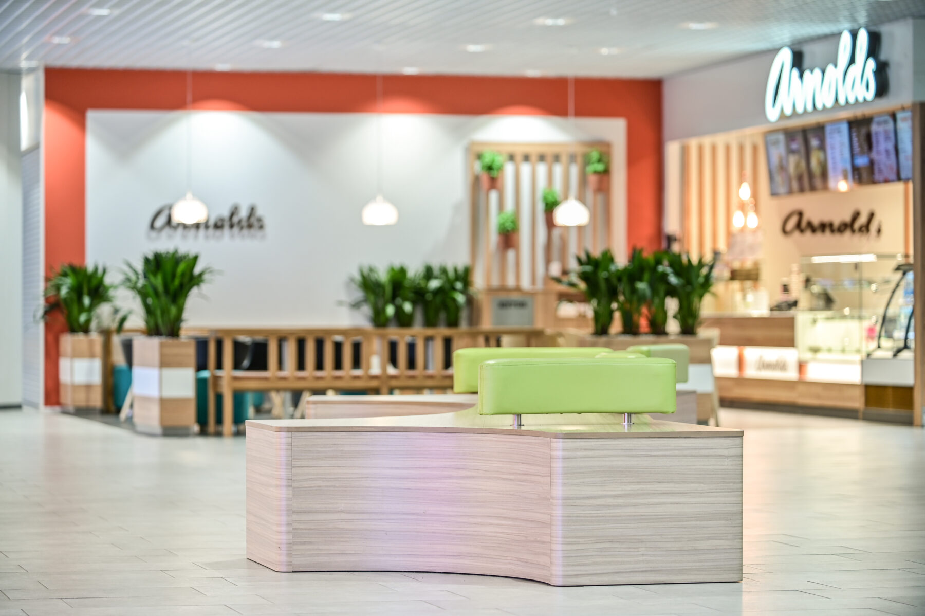 Ideapark Oulu C-aula julkitilan istuinkaluste, joka muodoltaan kolmisakarainen kaarevilla reunoilla. Vaalea puu laminaattipinta ja käsinojat kirkkaan vihreät. sisustussuunnittelu ja kalustemuotoilu Sisu interior.