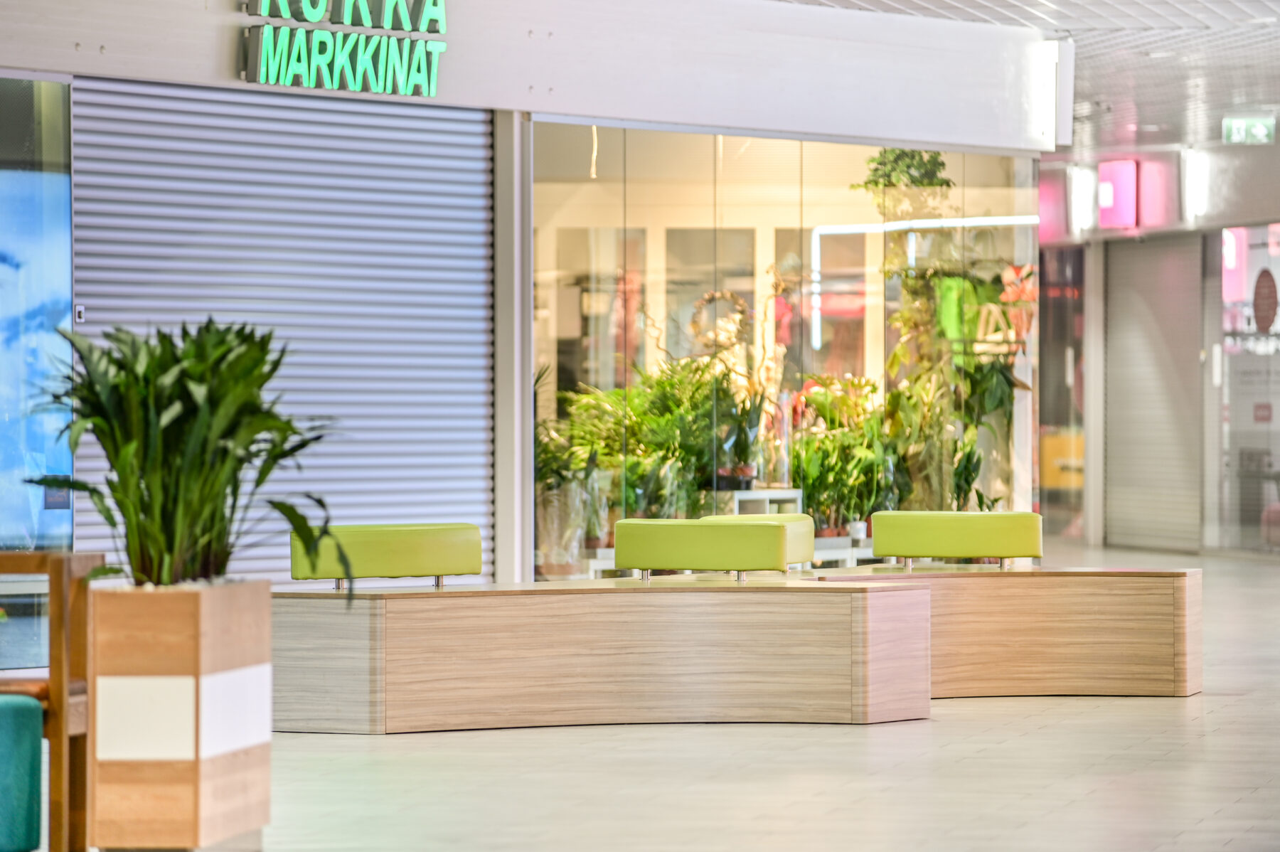 Ideapark Oulu C-aula julkitilan istuinkaluste, joka muodoltaan kolmisakarainen kaarevilla reunoilla. Vaalea puu laminaattipinta ja käsinojat kirkkaan vihreät. sisustussuunnittelu ja kalustemuotoilu Sisu interior.